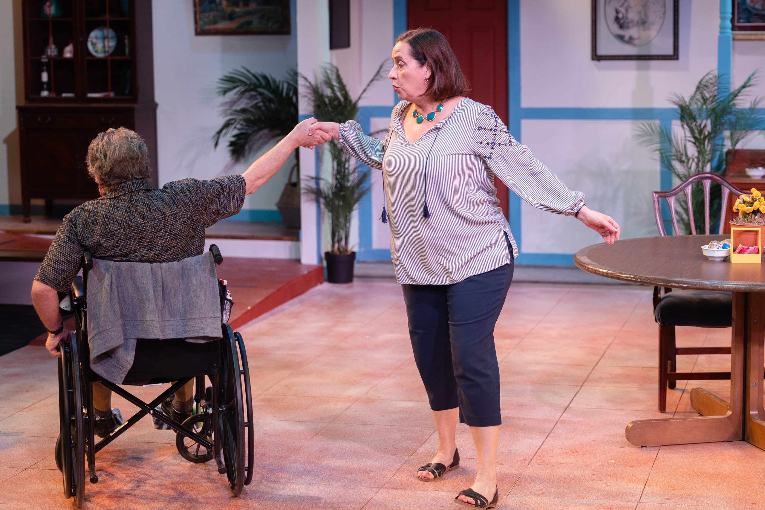 A man in a wheelchair dancing with a woman holding his hand